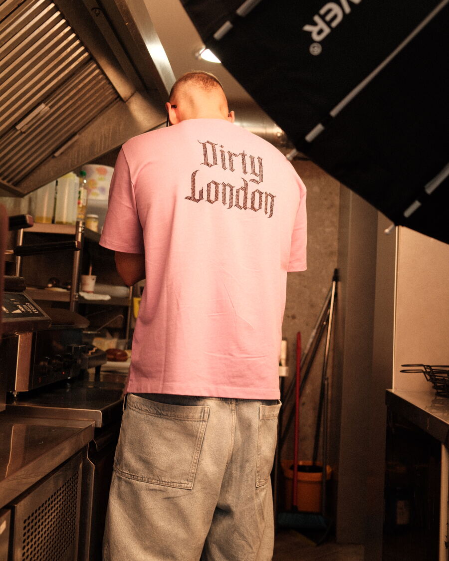 Cook in a pink Dirty London t-shirt on set
